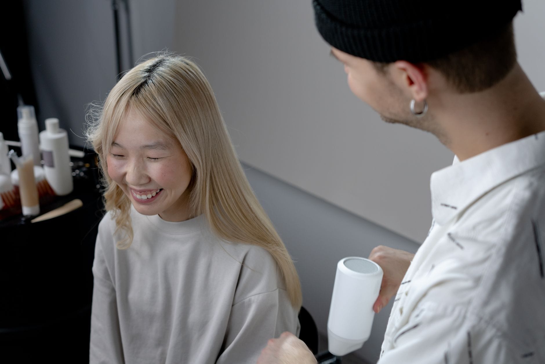 A hairstylist blow-drying a client's hair in a salon